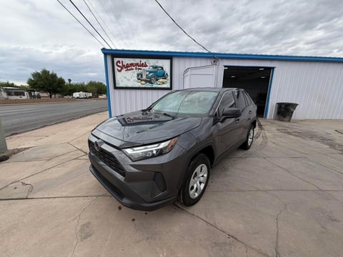 Black Toyota RAV4 parked outside Shamrocks auto shop with metal building and power lines in background